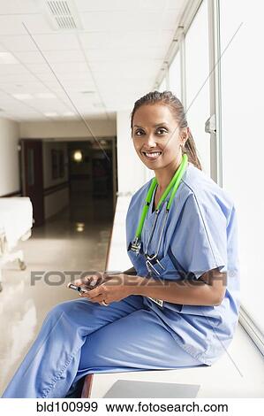 Stock Photo - Doctor text messaging on cell phone in hospital. Fotosearch