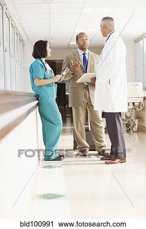 Stock Image - Doctors and drug salesman talking in hospital. Fotosearch
