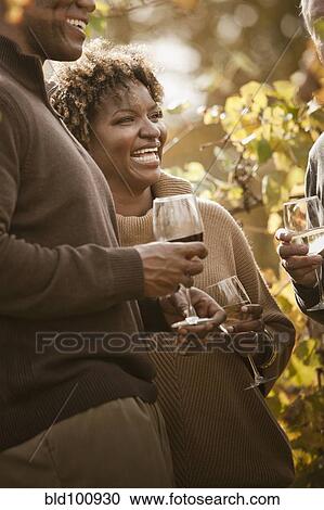 Stock Image - Friends drinking wine in vineyard. Fotosearch