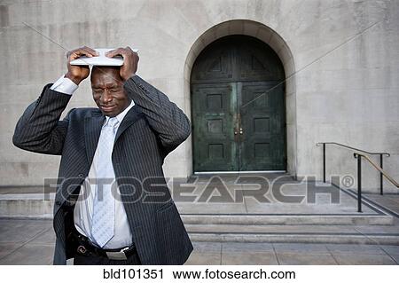 Stock Image - Frustrated businessman putting digital tablet on his head. Fotosearch