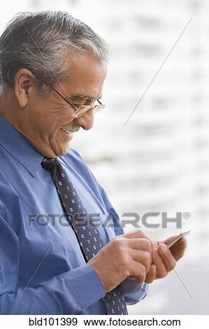 Stock Photo - Hispanic businessman text messaging on cell phone. Fotosearch