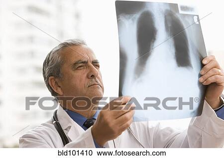 Stock Image - Hispanic doctor looking at x-ray. Fotosearch