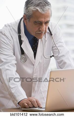 Hispanic doctor using laptop View Large Photo Image Stock Image - Hispanic doctor using laptop. Fotosearch