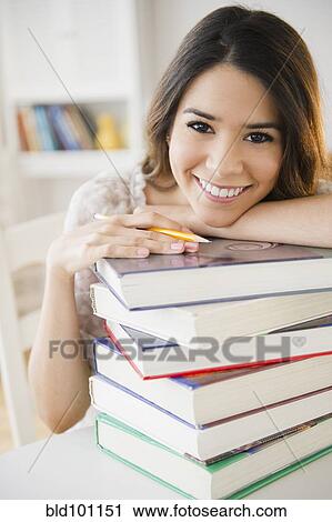 Stock Image - Hispanic student leaning on stack of books. Fotosearch