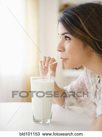 Stock Image - Hispanic woman drinking milk through straw. Fotosearch