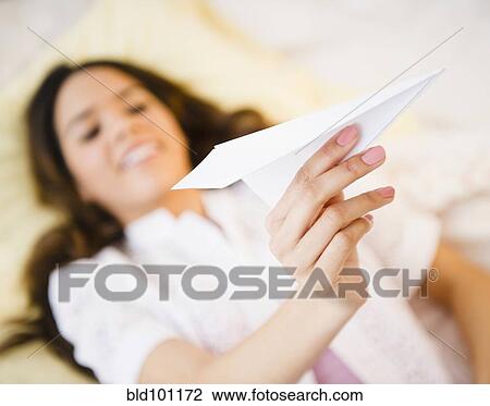 Stock Image - Hispanic woman holding paper airplane. Fotosearch