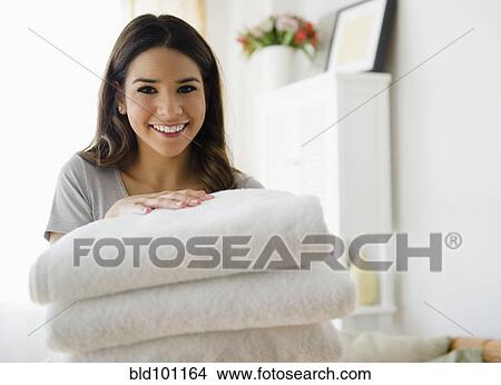 Picture - Hispanic woman holding stack of towels. Fotosearch