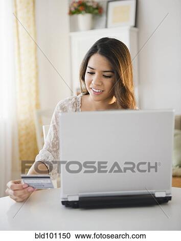 Stock Image - Hispanic woman shopping online with credit card. Fotosearch