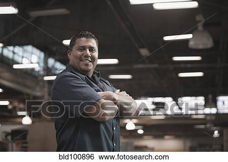 Stock Photograph - Hispanic worker standing in warehouse. Fotosearch