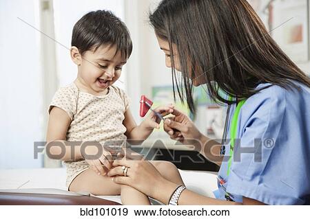 Stock Photo - Indian doctor testing baby's reflexes in doctor's office. Fotosearch