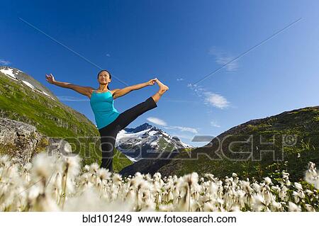 Stock Photo - Korean woman practicing yoga with mountain in background. Fotosearch