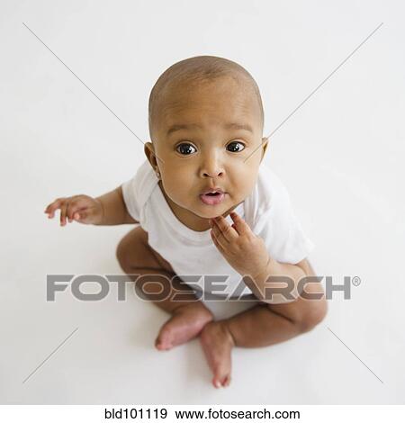 Stock Photo - Mixed race baby girl sitting on floor. Fotosearch