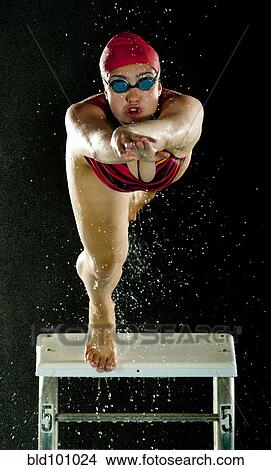 Picture - Mixed race swimmer diving off starting block. Fotosearch