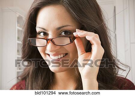 Picture - Mixed race woman adjusting eyeglasses. Fotosearch