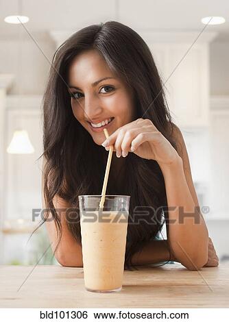 Stock Photograph - Mixed race woman drinking smoothie. Fotosearch