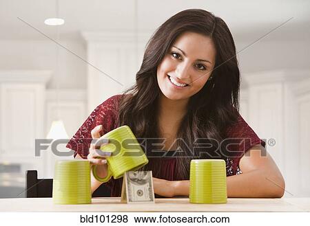 Stock Photo - Mixed race woman finding money underneath cup. Fotosearch