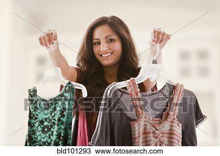 Stock Image - Mixed race woman holding clothing. Fotosearch