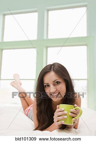 Mixed race woman laying in bed drinking coffee View Large Photo Image Stock Photo - Mixed race woman laying in bed drinking coffee. Fotosearch