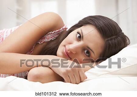 Stock Image - Mixed race woman laying in bed. Fotosearch