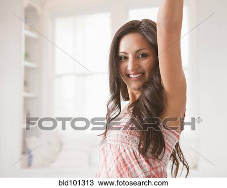 Stock Image - Mixed race woman with arm raised. Fotosearch