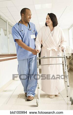 Picture - Nurse helping patient use walker in hospital. Fotosearch