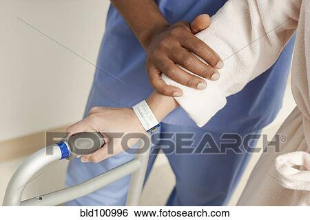 Stock Photograph - Nurse helping patient use walker in hospital. Fotosearch