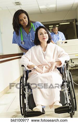 Stock Photo - Nurse pushing patient in wheelchair in hospital. Fotosearch