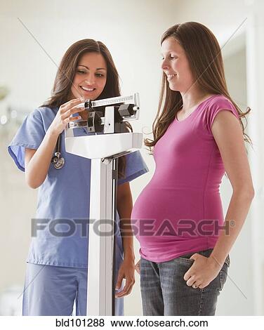 Stock Photo - Nurse weighing pregnant woman. Fotosearch