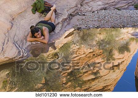 Stock Image - Persian woman resting near tranquil pool. Fotosearch