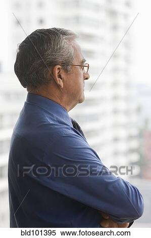 Stock Photography - Serious Hispanic businessman looking out window. Fotosearch