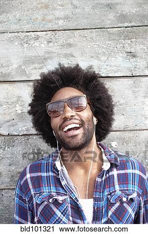 Stock Image - Smiling Black man listening to mp3 player. Fotosearch