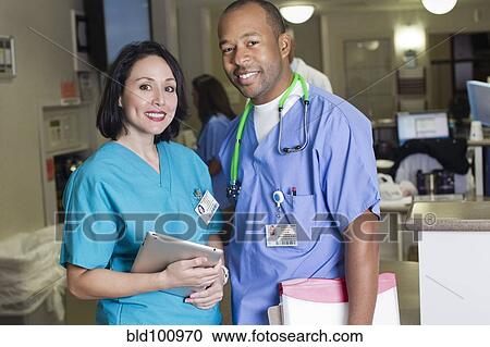 Stock Image - Smiling doctors standing in hospital. Fotosearch