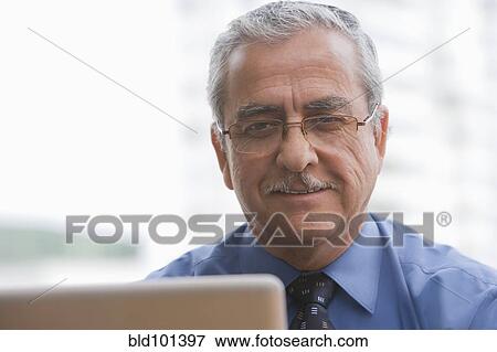 Smiling Hispanic businessman using laptop View Large Photo Image Stock Photo - Smiling Hispanic businessman using laptop. Fotosearch