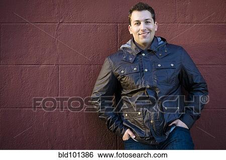 Smiling man leaning against wall View Large Photo Image Stock Photograph - Smiling man leaning against wall. Fotosearch