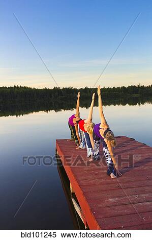 Stock Photography - Woman exercising on lake pier. Fotosearch