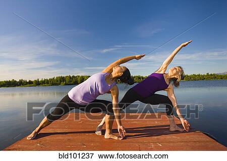 Stock Photo - Women stretching on lake pier. Fotosearch