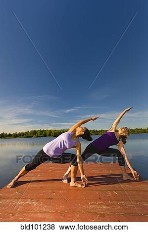 Stock Photo - Women stretching on lake pier. Fotosearch