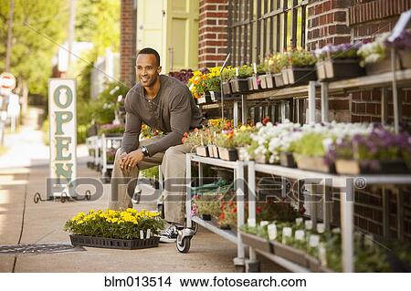 African American man sitting with flowers at flower shop View Large Photo Image Picture - African American man sitting with flowers at flower shop. Fotosearch