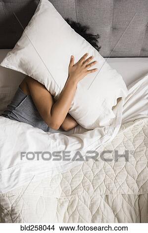 African American woman laying on bed hiding face under pillow View Large Photo Image Picture - African American woman laying on bed hiding face under pillow. Fotosearch