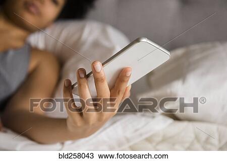 African American woman laying on bed texting on cell phone View Large Photo Image Stock Image - African American woman laying on bed texting on cell phone. Fotosearch