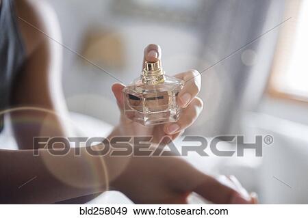 Stock Photo - African American woman spraying perfume on wrist. Fotosearch