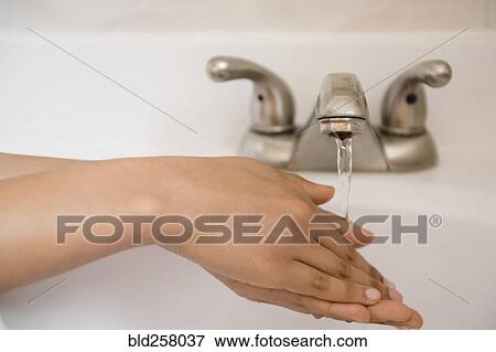 Stock Photo - African American woman washing hands with water. Fotosearch