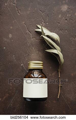 Picture - Alternative medicine jar with blank label near leaf. Fotosearch