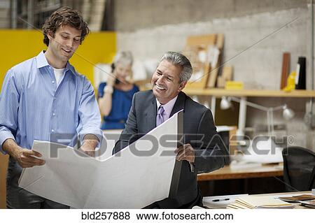 Stock Photo - Architects reading blue1ints in office. Fotosearch