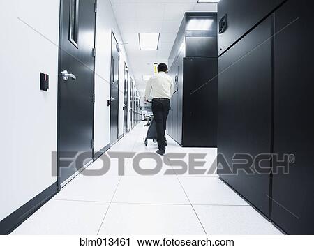 Stock Image - Asian businessman walking in server room. Fotosearch
