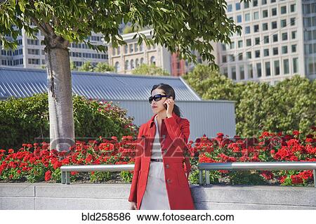 Stock Photograph - Asian businesswoman talking on cell phone outdoors. Fotosearch