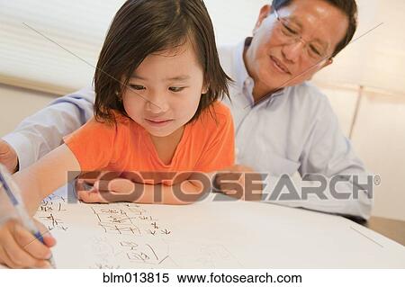 Stock Photography - Asian grandfather watching grandson writing. Fotosearch