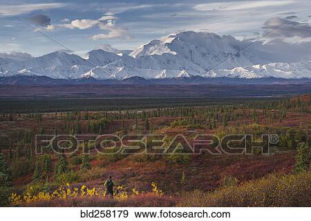 Stock Photo - Asian hiker admiring scenic view of mountain range. Fotosearch