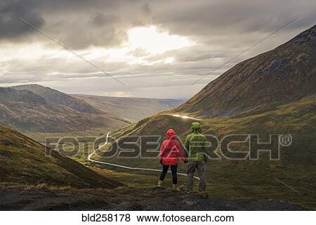 Asian hikers holding hands admiring scenic view of valley View Large Photo Image Stock Photo - Asian hikers holding hands admiring scenic view of valley. Fotosearch