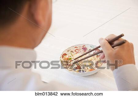 Asian man eating with chopsticks View Large Photo Image Stock Image - Asian man eating with chopsticks. Fotosearch